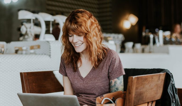 Lady improving the content on her website =- sat in a chair in front of a laptop