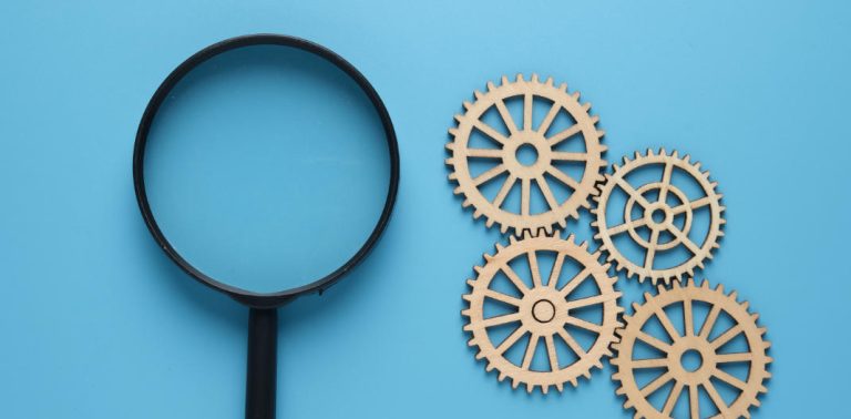 Magnifying glass next to a bunch of cogs